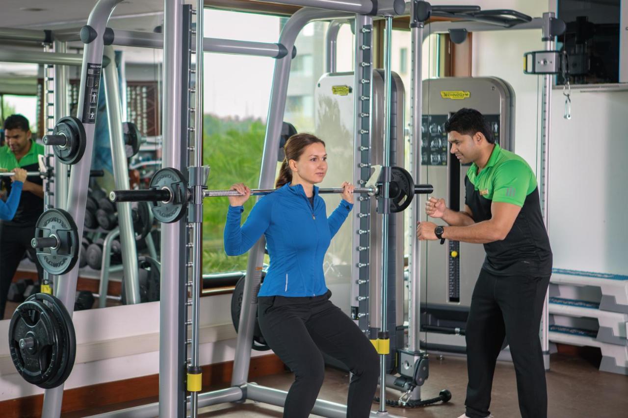 Jumeirah Messilah Beach Kuwait Koweït Extérieur photo A personal trainer assisting a woman with a squat